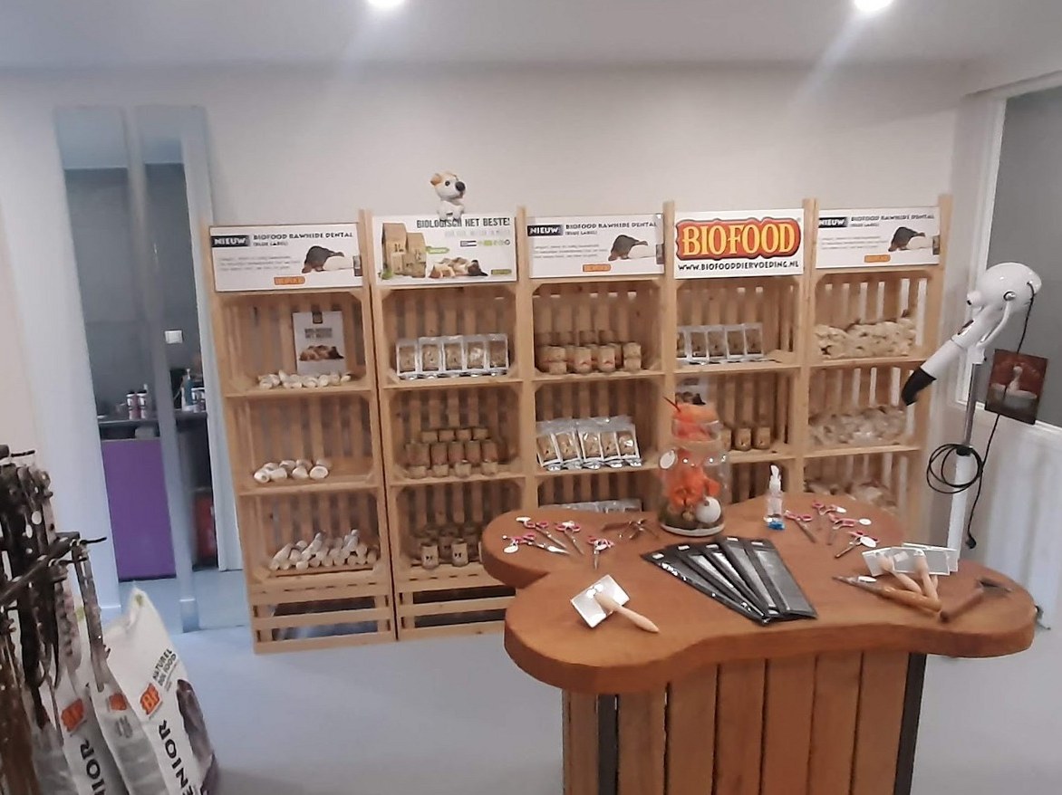 Houten kratten vol kauwsnacks en een houten tafel in de vorm van een bot met borstels en kammen